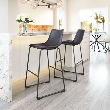 Two black bar stools in a modern kitchen setting with white cabinets and light wood flooring.