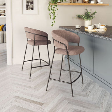 Two brown bar stools in a kitchen setting with a countertop and decor.