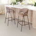 Two brown bar stools in front of a kitchen counter with plants in the background.