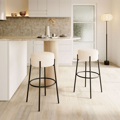 Modern kitchen with white bar stools and a light wood floor.