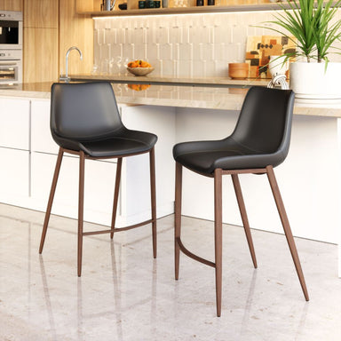Two black bar stools with wooden legs in a kitchen setting.