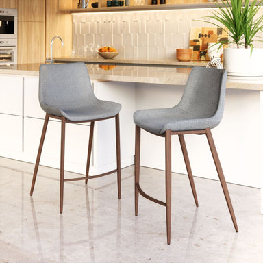 Two gray bar stools with wooden legs in a kitchen setting.