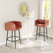 Two brown bar stools with black legs in front of a white table in a room with a decorative mirror.