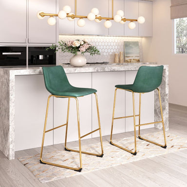 Two green bar stools with gold legs in a modern kitchen setting.