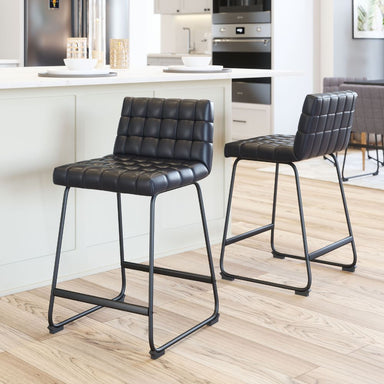 Two black bar stools with quilted seats in a kitchen setting.