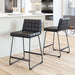 Two black bar stools with quilted seats in a kitchen setting.