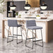 Two gray bar stools in a modern kitchen with marble countertops and pendant lights.