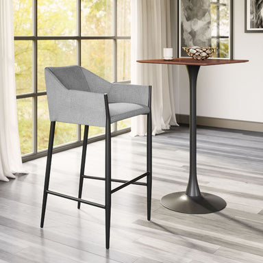 Gray bar stool next to a wooden table in a room with large windows.
