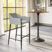 Gray bar stool next to a wooden table in a room with large windows.