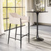 Modern bar stool with white cushioned seat next to a black bar table in a bright room with large windows.
