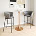 Two gray bar stools in front of a small round table with a gold base in a minimalistic room.