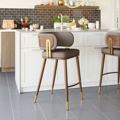 Modern bar stools with brown cushioned seats and gold legs in a kitchen setting.