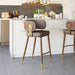 Modern bar stools with brown cushioned seats and gold legs in a kitchen setting.