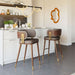 Modern kitchen with two bar stools featuring wooden frames and brown seats.