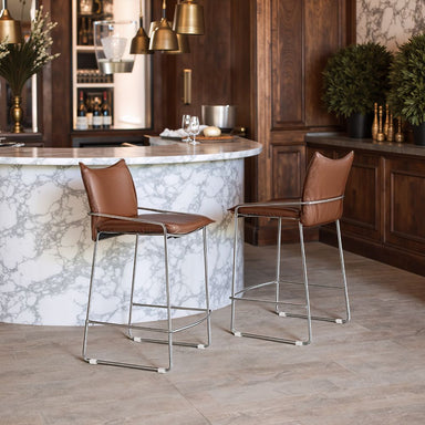 Two brown bar stools in front of a marble countertop in a kitchen setting.