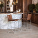 Two brown bar stools in front of a marble countertop in a kitchen setting.