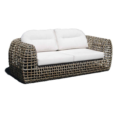 Wicker outdoor sofa with white cushions on a white background