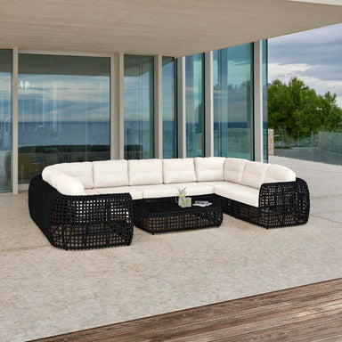 Modern outdoor furniture set with a white sectional sofa and black wicker chairs on a patio.