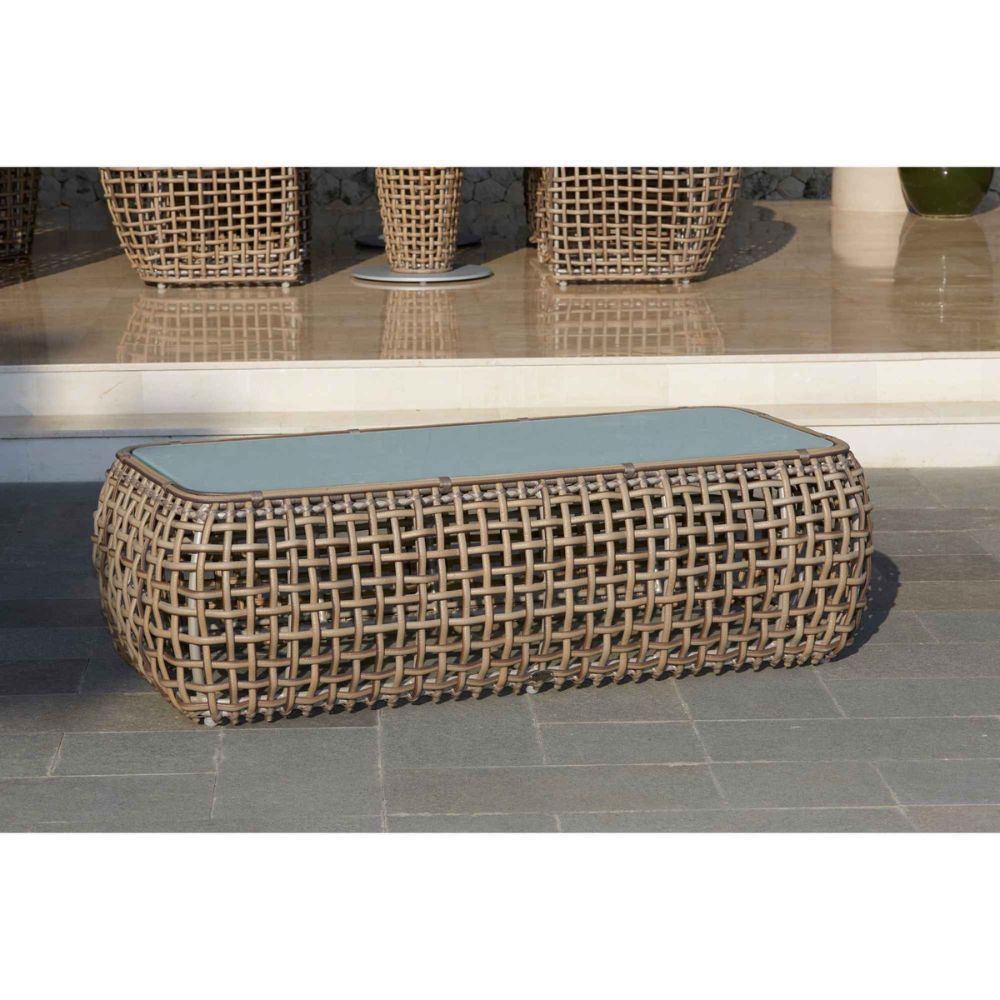 Woven outdoor bench with a light blue cushion on a tiled floor.