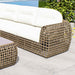 Wicker outdoor sofa with white cushions on a patio