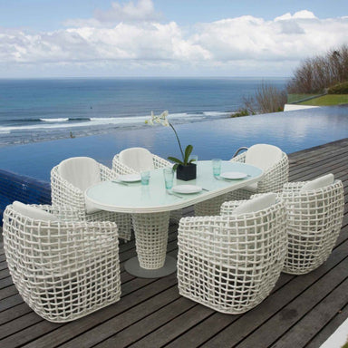Outdoor dining set with a table and chairs by an infinity pool with ocean view.