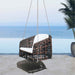Wicker swing chair with white cushion hanging on a patio with ocean view