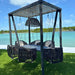 Outdoor swing set with black ropes and chairs against a scenic water background