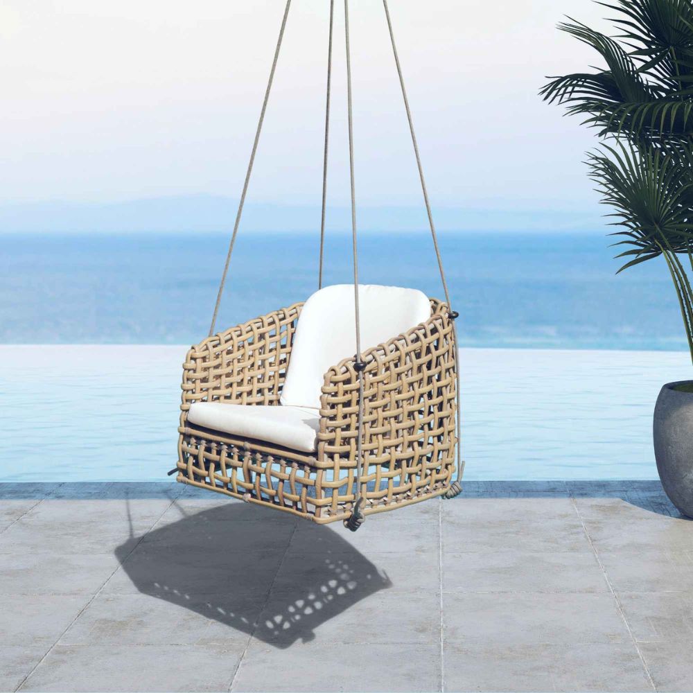 Wicker swing chair with white cushion on a patio with ocean view