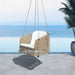 Wicker swing chair with white cushion on a patio with ocean view