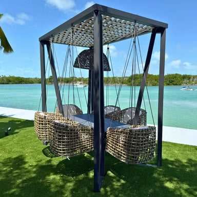 Outdoor swing set with woven chairs under a metal canopy by a waterfront.