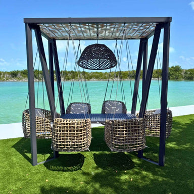 Outdoor swing set with wicker chairs and a canopy over a body of water.