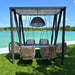 Outdoor swing set with wicker chairs and a canopy over a body of water.