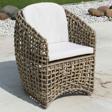 Woven outdoor chair with white cushion on a patio