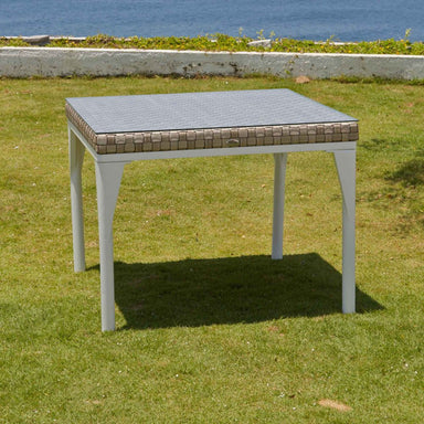 Square outdoor table with a textured top on grass with ocean view