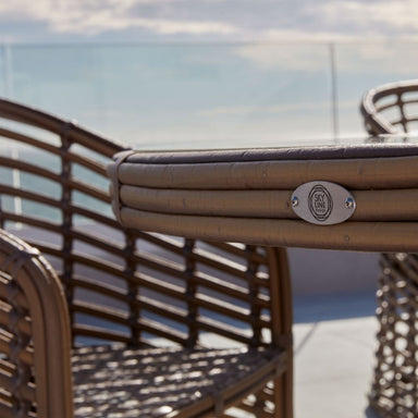 Close-up of a brown outdoor chair with a visible brand logo against a blurred background