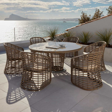 Outdoor dining set with round table and chairs on a patio overlooking water.