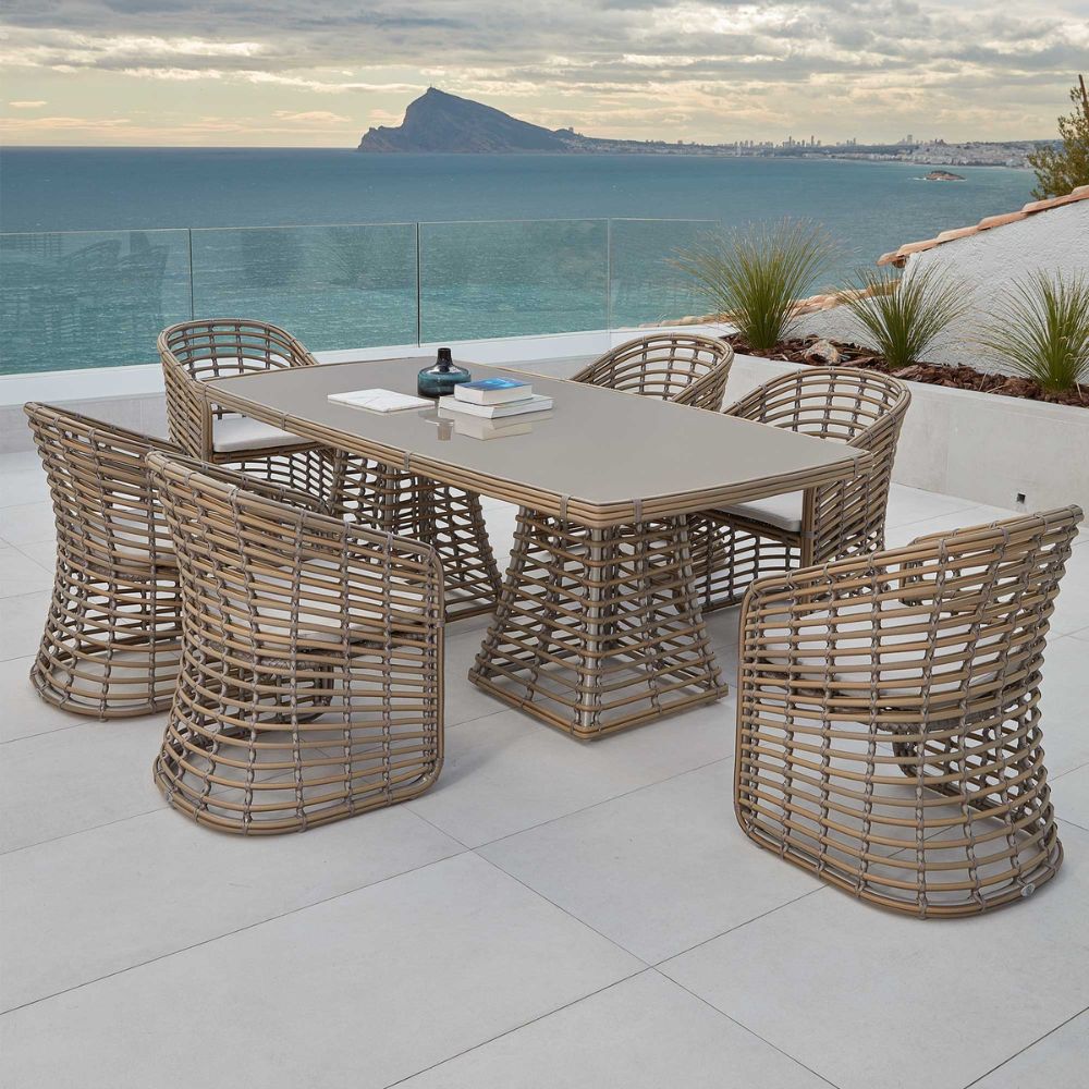 Outdoor dining set with a table and chairs on a patio overlooking the ocean.