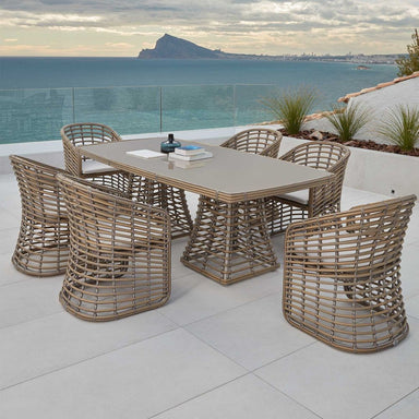 Outdoor dining set with a table and chairs on a patio overlooking the ocean.