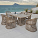 Outdoor dining set with a table and chairs on a patio overlooking the ocean.