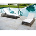 Two lounge chairs with white cushions on a patio by a pool.
