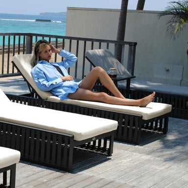 Woman relaxing on a lounge chair by the beach with a drink.