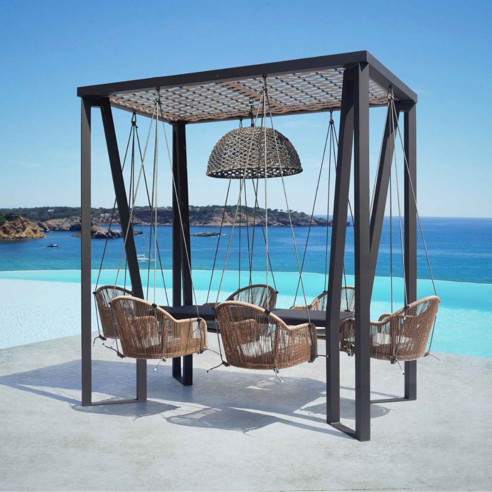 Outdoor seating area with wicker chairs and a hanging lamp, set against a scenic ocean view.