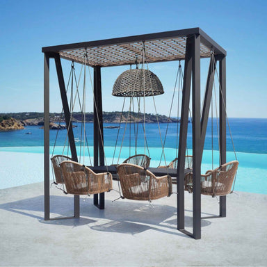 Outdoor seating area with wicker chairs and a hanging lamp, set against a scenic ocean view.