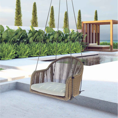 Woven chair swing with beige cushion in a modern outdoor setting with pool and greenery.
