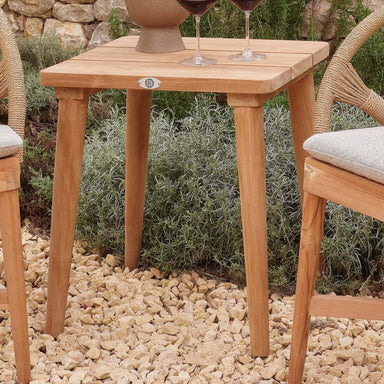 Wooden outdoor table with two wine glasses on a stone patio