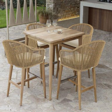 Outdoor dining set with wooden table and wicker chairs on a stone patio.