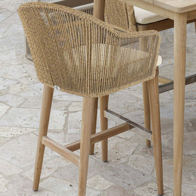 Woven chair with wooden legs on a stone patio