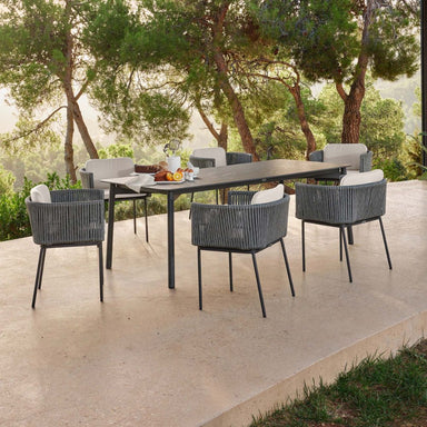 Outdoor dining set with a table and chairs on a patio with trees in the background