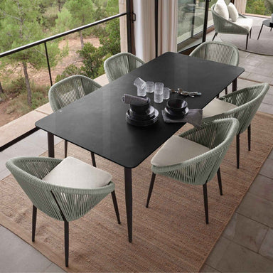 Outdoor dining set with black table and green chairs on a patio.