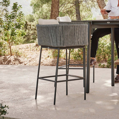 Gray woven bar stool with metal legs on a patio